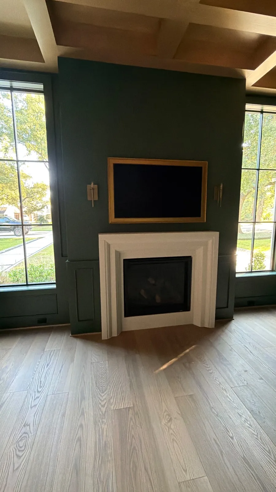 Samsung Frame TV with a gold frame mounted above a white fireplace on a green wall